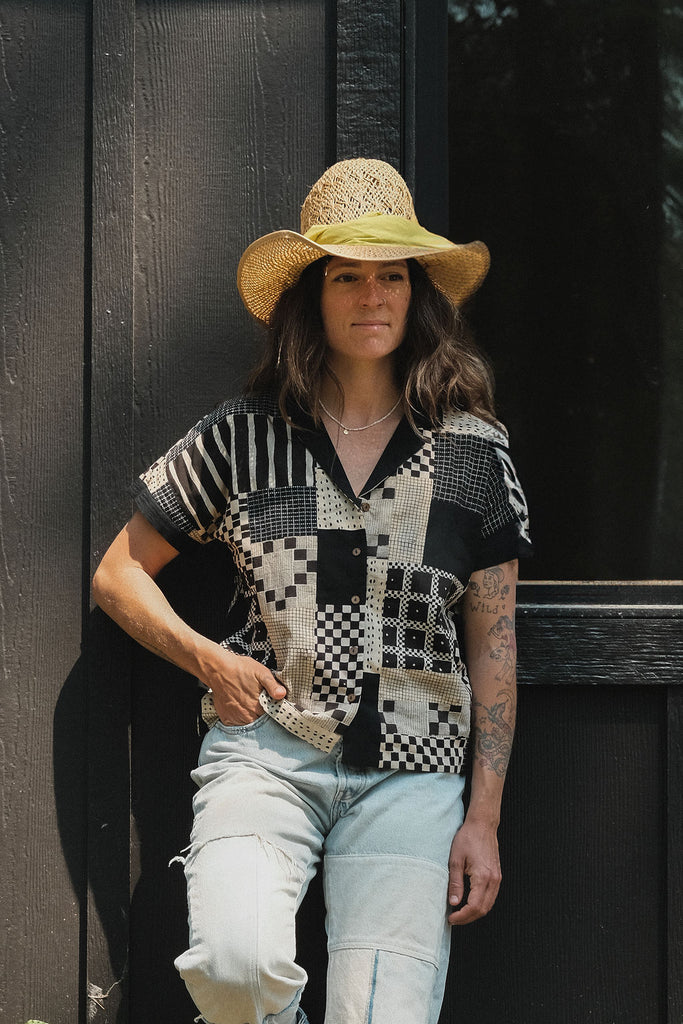 Black and tan hand block-printed patchwork top with short sleeves and solid black cuffs. Features a front placket opening with buttons and is fully lined for added comfort. Crafted from lightweight, non-stretchy cotton that feels soft and breathable on the skin. Ethically made using traditional techniques, with each piece being one-of-a-kind due to slight variations in color and pattern. Falls 22” from the shoulder and fits true to size—perfect for everyday wear with an artisanal, modern touch.