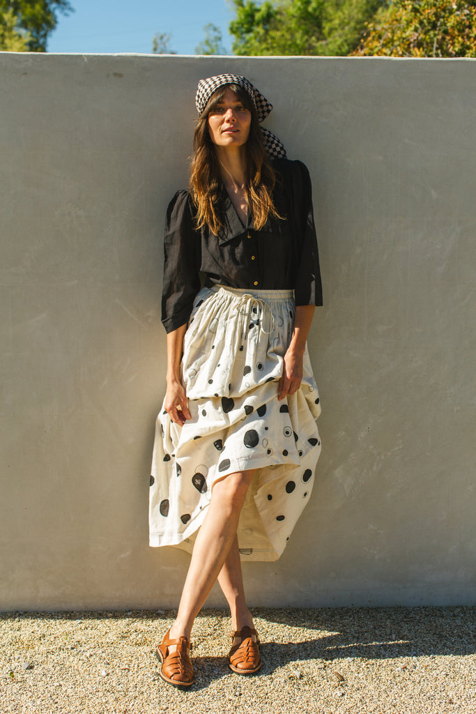 This Raindrops skirt is meticulously crafted from hand-woven fabric. Its exquisite appliqué work adds a touch of enchantment, elevating any ensemble. With its timeless black and white palette, this skirt effortlessly complements a variety of tops and shirts, ensuring versatility and sophistication with every wear.