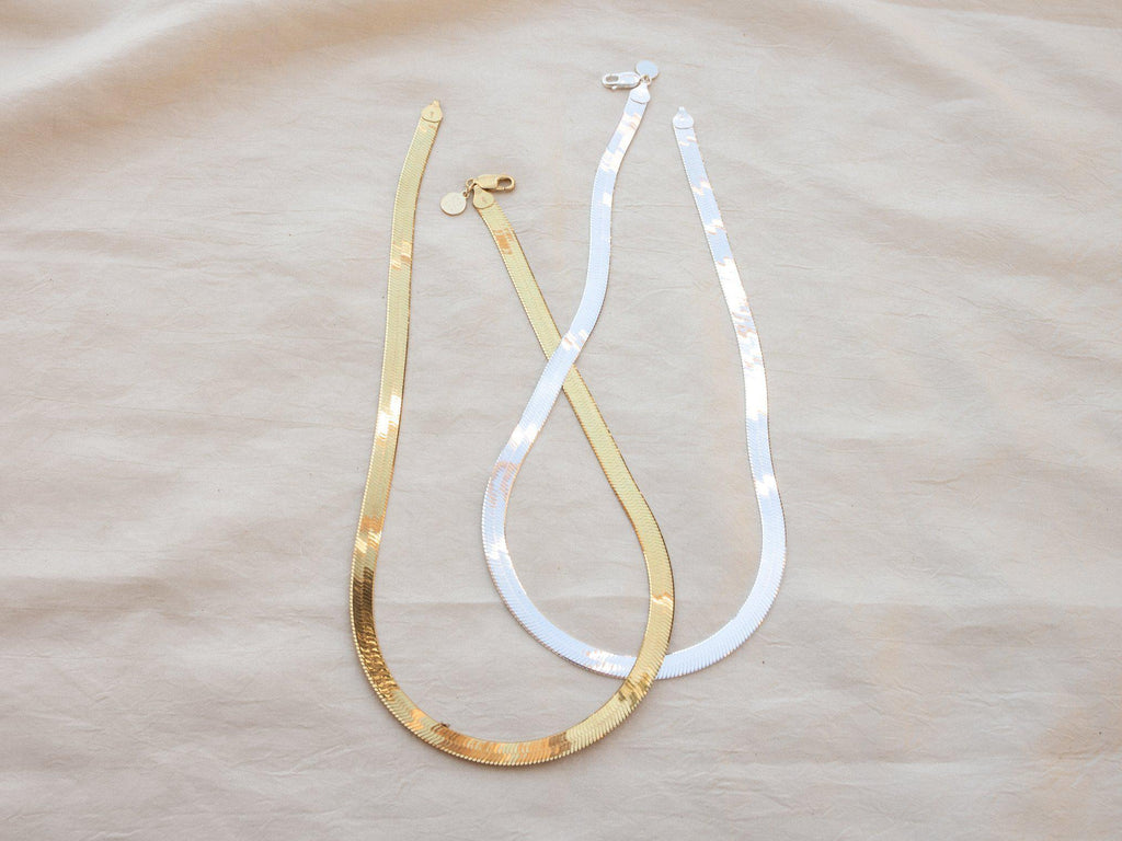 Introducing our vintage-inspired silver herringbone necklace, designed to captivate with its bold, flat chain. Crafted in Italy, this piece features a striking 7mm thick chain and an 18" length, reflecting light beautifully for a sophisticated statement. This sterling silver necklace combines classic style with modern elegance